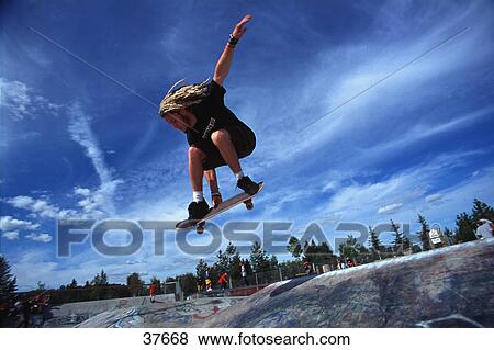 Stock Photo - Boarder performing stunt at skate park. Fotosearch