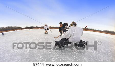 Boys playing hockey on frozen pond View Large Photo Image Picture - Boys playing hockey on frozen pond. Fotosearch