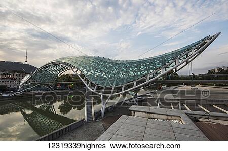 Stock Photograph - Bridge of Peace, a bow-shaped pedestrian bridge over the Mtkvari (Kura) River; Tbilisi, Georgia. Fotosearch