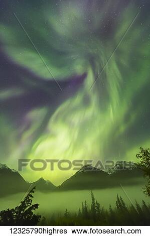 Stock Photograph - Bright green aurora borealis dances over the Kenai Mountains, Moose Pass, Kenai Peninsula, South-central Alaska; Alaska, United States of America. Fotosearch