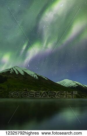 Stock Photograph - Bright green aurora borealis dances over the Kenai Mountains, Summit Lake reflects the skies in the foreground, Moose Pass, Kenai Peninsula, South-central Alaska; Alaska, United States of America. Fotosearch