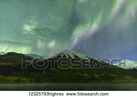 Stock Photograph - Bright green aurora borealis dances over the Kenai Mountains, Summit Lake reflects the skies in the foreground, Moose Pass, Kenai Peninsula, South-central Alaska; Alaska, United States of America. Fotosearch