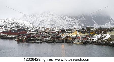 Buildings and boats along the waterfront under a cloudy sky with snow covered mountains; Lofoten Islands, Nordland, Norway View Large Photo Image Stock Photograph - Buildings and boats along the waterfront under a cloudy sky with snow covered mountains; Lofoten Islands, Nordland, Norway. Fotosearch