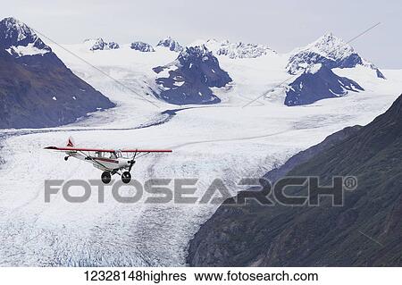 Stock Photograph - Bush plane in flight over Grewingk Glacier, Kachemak Bay State Park, Southcentral Alaska, USA. Fotosearch