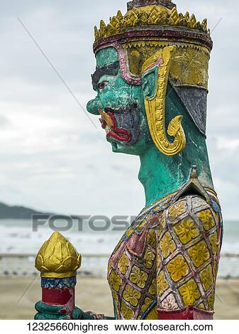 Stock Photograph - Close-up of a colourful, painted statue and the Gulf of Thailand in the background; Ko Samui, Chang Wat Surat Thani, Thailand. Fotosearch
