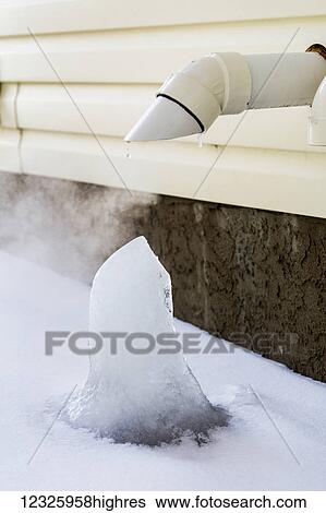 Stock Photograph - Close-up of furnace exhaust pipe on exterior of house with ice block forming; Calgary, Alberta, Canada. Fotosearch