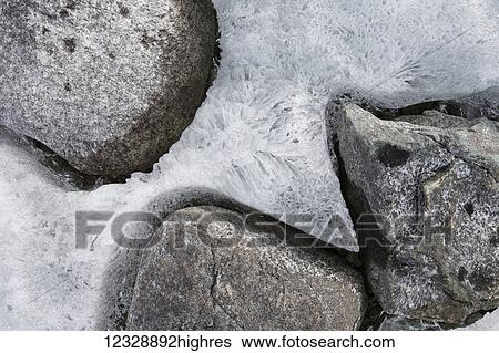 Stock Photograph - Close-up of ice frozen around rocks; Alaska, United States of America. Fotosearch