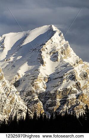 Stock Photograph - Close up of snow covered mountain peak with blue sky and clouds; Kananaskis Country, Alberta, Canada. Fotosearch