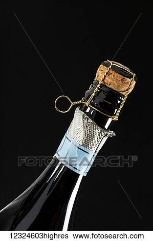 Close-up of the neck of a sparkling wine bottle with silver foil and wire cage holding cork on a black background; Calgary, Alberta, Canada View Large Photo Image Stock Photograph - Close-up of the neck of a sparkling wine bottle with silver foil and wire cage holding cork on a black background; Calgary, Alberta, Canada. Fotosearch