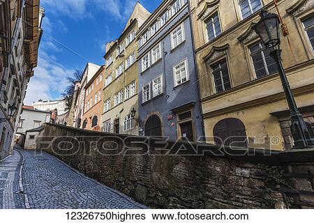 Colourful residential buildings and a wall along a narrow cobblestone road; Prague, Czechia View Large Photo Image Stock Photograph - Colourful residential buildings and a wall along a narrow cobblestone road; Prague, Czechia. Fotosearch