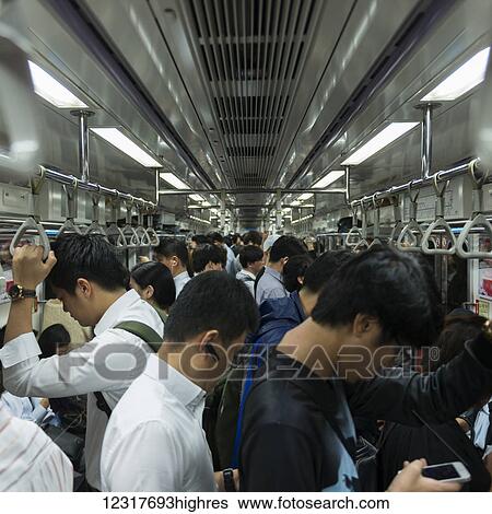 Stock Photograph - Commuters standing in a full subway train; Seoul, South Korea. Fotosearch