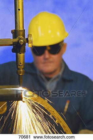 Stock Image - Construction worker monitoring steel cutter. Fotosearch