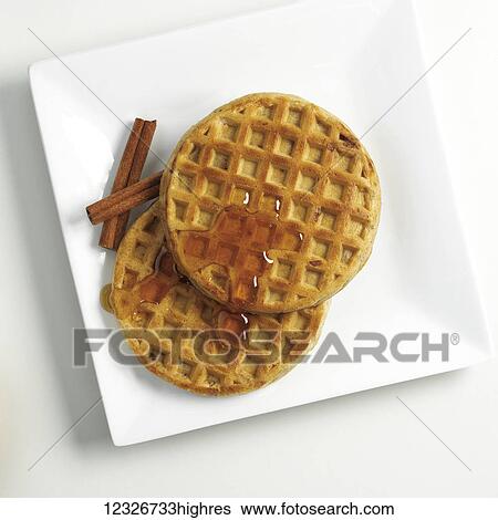 Stock Photograph - Directly above waffles with syrup and cinnamon sticks on a white plate. Fotosearch