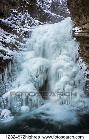 Dramatic iced waterfalls with open water at the base along a snowy rock cliff; Banff, Alberta, Canada View Large Photo Image Stock Photograph - Dramatic iced waterfalls with open water at the base along a snowy rock cliff; Banff, Alberta, Canada. Fotosearch