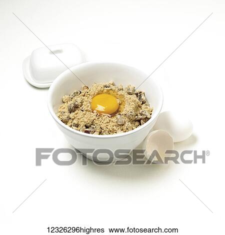 Stock Photograph - Dry ingredient for cookie dough in a bowl with a cracked egg on top on a white background. Fotosearch