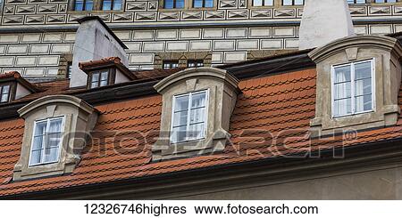 Stock Photograph - Facade of a building with three windows, tile and chimneys; Prague, Czechia. Fotosearch