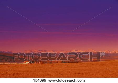 Stock Photo - Farm buildings and field with mountains in the background. Fotosearch