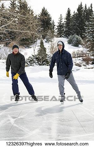 Father and son skating on pond with snow covered bridge in the background; Calgary, Alberta, Canada View Large Photo Image Stock Photograph - Father and son skating on pond with snow covered bridge in the background; Calgary, Alberta, Canada. Fotosearch