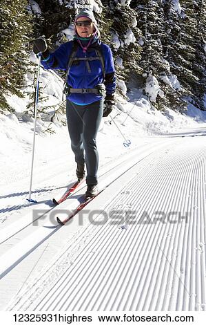 Stock Photograph - Female cross country skier on a freshly groomed track set trail; Kananaskis Country, Alberta, Canada. Fotosearch