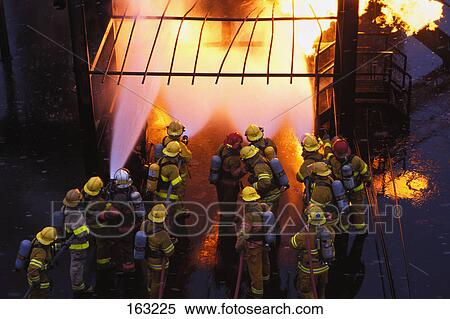 Stock Photography - Firemen spraying water on fire. Fotosearch