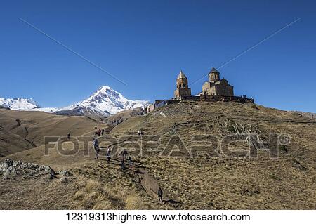 Stock Photograph - Gergeti Trinity Church with the Caucasus Mountains in the background; Kazbegi, Mtskheta-Mtianeti, Georgia. Fotosearch