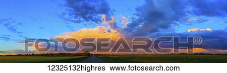 Glowing golden clouds over green fields and a country road at sunset; Alberta, Canada View Large Photo Image Stock Photograph - Glowing golden clouds over green fields and a country road at sunset; Alberta, Canada. Fotosearch