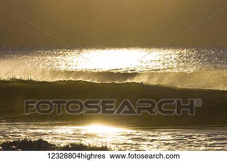 Stock Photograph - Golden sunlight reflecting on the surface of the water and waves in Kachemak Bay; Homer, Alaska, United States of America. Fotosearch