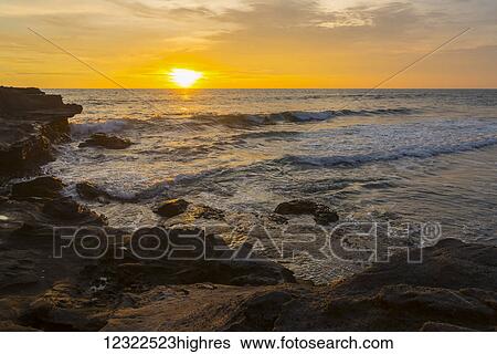 Golden sunset over the ocean with a view of the coastline; Bali Island, Indonesia View Large Photo Image Stock Photograph - Golden sunset over the ocean with a view of the coastline; Bali Island, Indonesia. Fotosearch