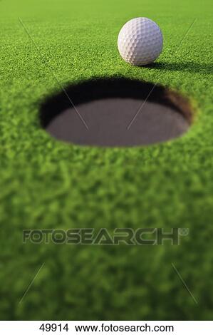 Golf ball on lip of cup View Large Photo Image Picture - Golf ball on lip of cup. Fotosearch