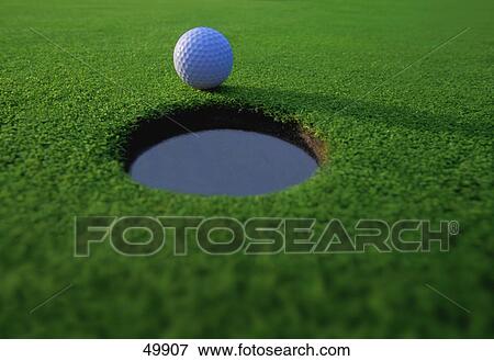 Stock Photo - Golf ball on lip of cup. Fotosearch