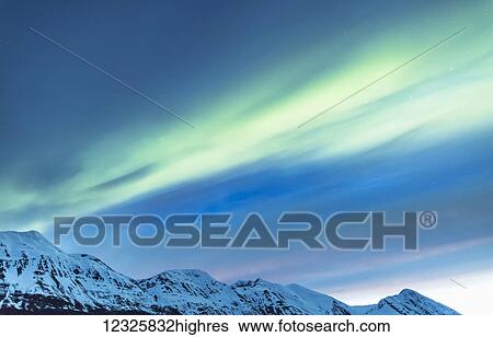 Stock Photograph - Green Aurora Borealis dances over partly cloudy skies above the Kenai Mountains, Moose Pass, Kenai Peninsula, South-central Alaska; Alaska, United States of America. Fotosearch