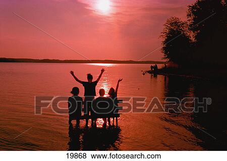 Stock Photo - Group on bench in lake at sunset. Fotosearch