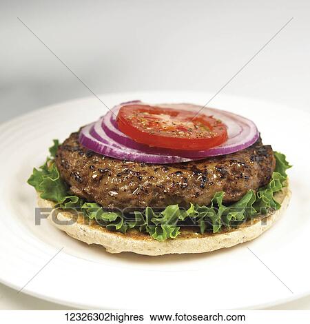 Stock Photograph - Hamburger patty with onion, lettuce and tomato on flatbread. Fotosearch