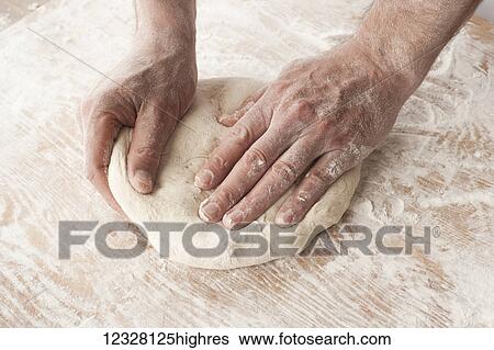 Stock Photograph - Hands working with pizza dough on a wooden floured surface. Fotosearch