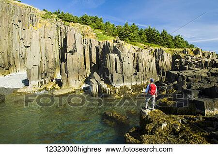 Stock Photograph - Hiker along basalt rock cliffs, Bay of Fundy; Brier Island, Nova Scotia, Canada. Fotosearch