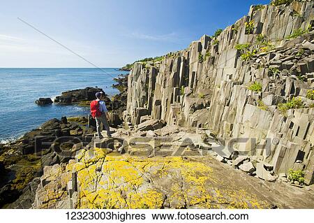 Stock Photograph - Hiker along basalt rock cliffs, Bay of Fundy; Brier Island, Nova Scotia, Canada. Fotosearch