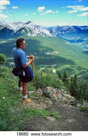 Stock Image - Hiker looking at view of valley. Fotosearch