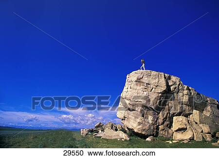 Stock Image - Hiker on huge boulder. Fotosearch