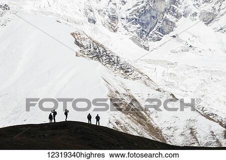 Stock Photograph - Hikers against the backdrop of Mount Shkhara in the Greater Caucasus Range; Ushguli, Samegrelo-Zemo Svaneti, Georgia. Fotosearch