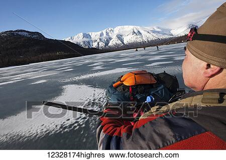 Stock Photograph - Hunter on an ATV during a freshwater harbor seal hunt, Lake Iliamna, Pedro Bay, Southcentral Alaska, USA. Fotosearch