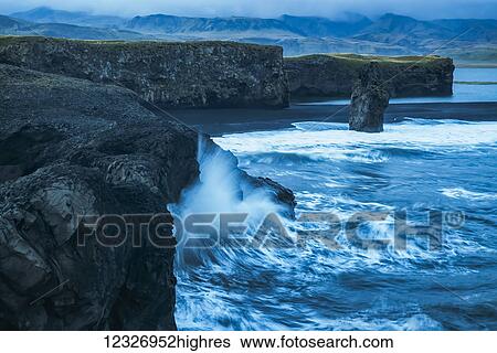 Stock Photograph - Large waves splash against the cliff sides of Dryholaey, Southern Iceland; Iceland. Fotosearch