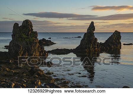 Stock Photograph - Lava pillars at sunrise along the Strandir Coast; West Fjords, Iceland. Fotosearch