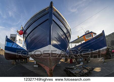 Stock Photograph - Low angle view of the bow of a fishing boat on the shore for maintenance; Seahouses, Northumberland, England. Fotosearch