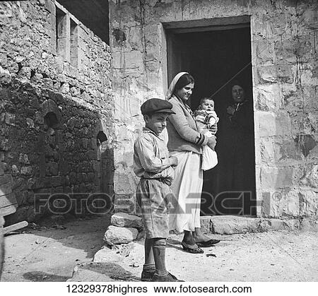 Stock Photograph - Magic lantern slide circa 1900. Victorian. Photographic image of boy, lady and baby in Isreal outside old house. Fotosearch