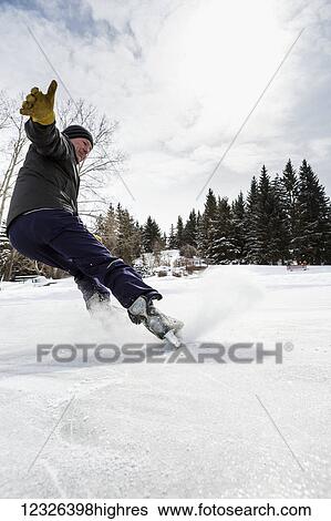Male gliding to a stop on skates with ice spray; Calgary, Alberta, Canada View Large Photo Image Stock Photograph - Male gliding to a stop on skates with ice spray; Calgary, Alberta, Canada. Fotosearch