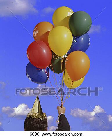 Stock Image - Man holding balloons and party hat. Fotosearch