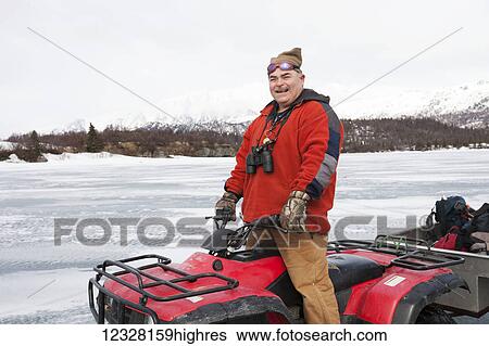 Stock Photograph - Man on an ATV on a frozen Lake Iliamna, Pedro Bay, Southcentral Alaska, USA. Fotosearch