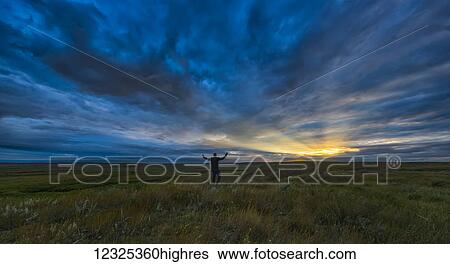Man standing with his arms spread open at daybreak in Grasslands National Park; Saskatchewan, Canada View Large Photo Image Stock Photograph - Man standing with his arms spread open at daybreak in Grasslands National Park; Saskatchewan, Canada. Fotosearch