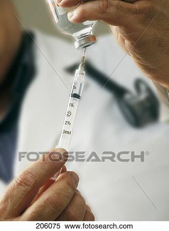 Stock Photography - Medical personnel drawing injection from vial. Fotosearch