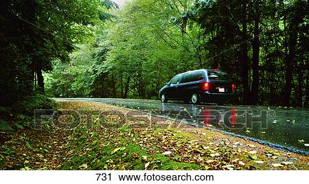 Stock Image - Minivan on wet country road. Fotosearch